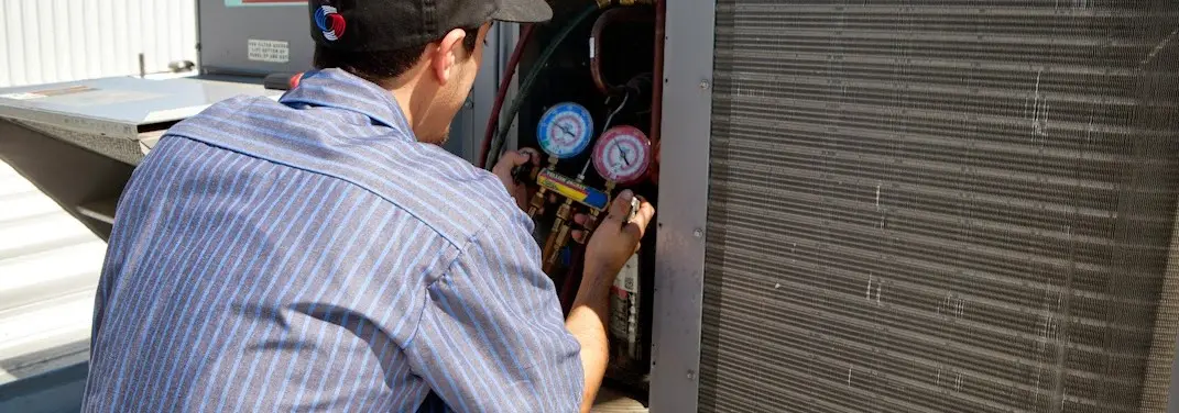 HVAC technician servicing a condenser unit in Fridley
